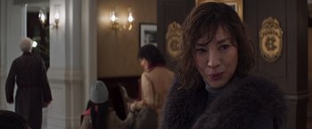 Movie still from “Crazy Rich Asians” (2018), directed by Jon M. Chu – A woman in a fur coat is looking into the camera; Close Up shot, Over the shoulder angle