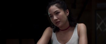 Movie still from “Crazy Rich Asians” (2018), directed by Jon M. Chu – A woman with a red necklace is sitting in a dark room; Close Up shot, Over the shoulder angle