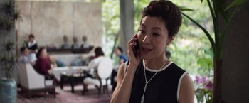Movie still from “Crazy Rich Asians” (2018), directed by Jon M. Chu – A woman talking on a cell phone while wearing a necklace; Close Up shot, High angle
