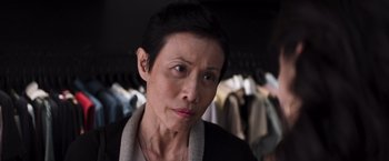 Movie still from “Crazy Rich Asians” (2018), directed by Jon M. Chu – An older woman with short black hair looking at the camera; Close Up shot, Over the shoulder angle