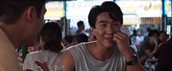 Movie still from “Crazy Rich Asians” (2018), directed by Jon M. Chu – A man sitting in front of a group of people; Close Up shot, Over the shoulder angle