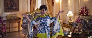 Movie still from “Crazy Rich Asians” (2018), directed by Jon M. Chu – A woman in a yellow and blue dress is posing for a picture; Medium shot, Low angle