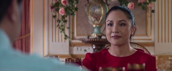 Movie still from “Crazy Rich Asians” (2018), directed by Jon M. Chu – A woman sitting at a table in front of a vase; Close Up shot, Over the shoulder angle