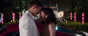 Movie still from “Crazy Rich Asians” (2018), directed by Jon M. Chu – A man and a woman standing next to each other in front of a car; Medium shot, Over the shoulder angle