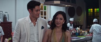 Movie still from “Crazy Rich Asians” (2018), directed by Jon M. Chu – A man standing next to a woman in front of a group of people; Close Up shot, Over the shoulder angle