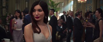 Movie still from “Crazy Rich Asians” (2018), directed by Jon M. Chu – A woman in a white dress standing in front of a group of people; Close Up shot, Over the shoulder angle