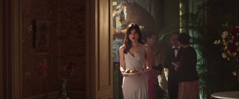 Movie still from “Crazy Rich Asians” (2018), directed by Jon M. Chu – A woman holding a plate of food in a room; Medium shot, Over the shoulder angle