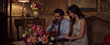 Movie still from “Crazy Rich Asians” (2018), directed by Jon M. Chu – A man and a woman sitting in front of a flower arrangement; Medium shot, Over the shoulder angle