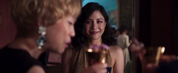 Movie still from “Crazy Rich Asians” (2018), directed by Jon M. Chu – A woman in a gold dress is talking to a man in a black suit; Close Up shot, Over the shoulder angle