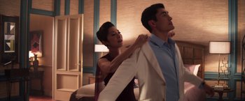 Movie still from “Crazy Rich Asians” (2018), directed by Jon M. Chu – A woman helping a man put on a jacket; Medium shot, Over the shoulder angle