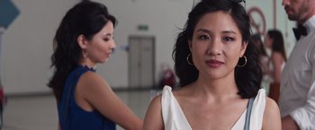 Movie still from “Crazy Rich Asians” (2018), directed by Jon M. Chu – A woman standing next to another woman in front of a building; Close Up shot, Over the shoulder angle
