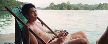 Movie still from “Crazy Rich Asians” (2018), directed by Jon M. Chu – A man sitting in a boat on a body of water; Medium shot, High angle