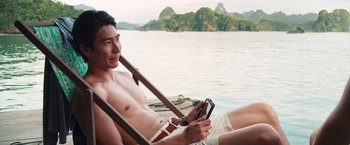Movie still from “Crazy Rich Asians” (2018), directed by Jon M. Chu – A man sitting in a boat on a body of water; Medium shot, High angle