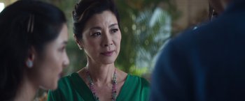 Movie still from “Crazy Rich Asians” (2018), directed by Jon M. Chu – An older asian woman wearing a green dress; Close Up shot, Over the shoulder angle