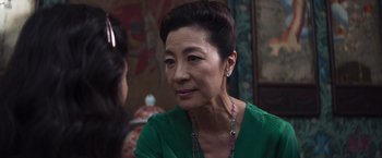 Movie still from “Crazy Rich Asians” (2018), directed by Jon M. Chu – An older woman wearing a green shirt and wearing a necklace; Close Up shot, Over the shoulder angle