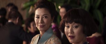Two asian women standing next to each other in front of a crowd