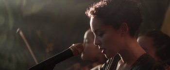 Movie still from “Crazy Rich Asians” (2018), directed by Jon M. Chu – A person holding a microphone; Close Up shot, Low angle