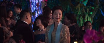 Movie still from “Crazy Rich Asians” (2018), directed by Jon M. Chu – A group of people standing around a room; Medium shot, Over the shoulder angle