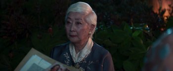 Movie still from “Crazy Rich Asians” (2018), directed by Jon M. Chu – An older woman with white hair looking at the camera; Close Up shot, Over the shoulder angle