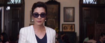Movie still from “Crazy Rich Asians” (2018), directed by Jon M. Chu – A woman wearing sunglasses standing in front of a painting; Close Up shot, Low angle