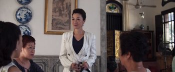 Movie still from “Crazy Rich Asians” (2018), directed by Jon M. Chu – A woman in a white jacket holding a cell phone in her hands; Medium shot, Over the shoulder angle