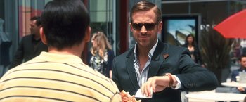 Movie still from “Crazy, Stupid, Love.” (2011), directed by Glenn Ficarra – A man in a suit and sunglasses eating a piece of pizza; Medium shot, Over the shoulder angle