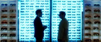 Movie still from “Crazy, Stupid, Love.” (2011), directed by Glenn Ficarra – Two men standing next to each other in front of a wall of sunglasses; Medium shot, Over the shoulder angle
