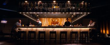 Movie still from “Crazy, Stupid, Love.” (2011), directed by Glenn Ficarra – Two men are sitting at a bar in front of a wall of bottles; Wide shot, High angle
