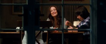 Movie still from “Crazy, Stupid, Love.” (2011), directed by Glenn Ficarra – A woman sitting at a dining table smiling; Medium shot, Over the shoulder angle