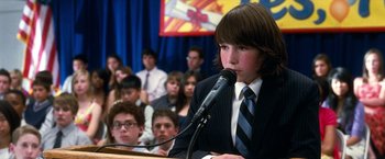 Movie still from “Crazy, Stupid, Love.” (2011), directed by Glenn Ficarra – A boy in a suit is talking into a microphone; Close Up shot, Over the shoulder angle
