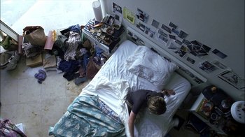 Movie still from “Crazy/Beautiful” (2001), directed by John Stockwell – A person laying on a bed in a room with a lot of clutter around it; Wide shot, Overhead angle