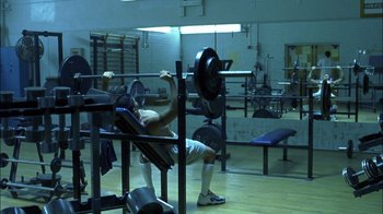 Movie still from “Crazy/Beautiful” (2001), directed by John Stockwell – A man is lifting a barbell in a gym; Wide shot, Over the shoulder angle