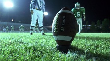Movie still from “Crazy/Beautiful” (2001), directed by John Stockwell – A football on a field at night; Extreme Close Up shot, Overhead angle