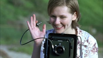 Movie still from “Crazy/Beautiful” (2001), directed by John Stockwell – A woman holding a camera and waving to someone; Close Up shot, Over the shoulder angle