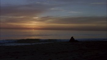 Movie still from “Crazy/Beautiful” (2001), directed by John Stockwell – A person sitting on the beach watching the sun go down over the ocean; Extreme Wide shot, High angle