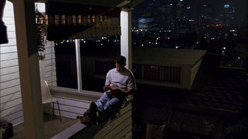 Movie still from “Crazy/Beautiful” (2001), directed by John Stockwell – A man sitting on a porch at night; Wide shot, High angle