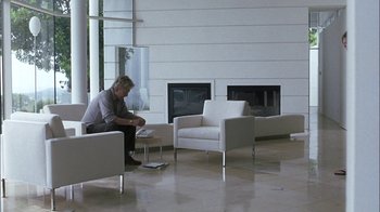 Movie still from “Crazy/Beautiful” (2001), directed by John Stockwell – A man sitting on a chair in a room; Wide shot, High angle