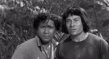 Movie still from “Creature from the Black Lagoon” (1954), directed by Jack Arnold – Two men standing next to each other near a forest; Close Up shot, Low angle