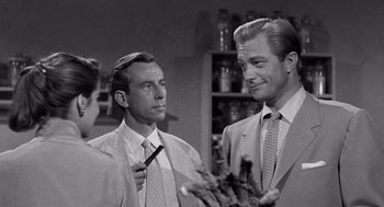 Movie still from “Creature from the Black Lagoon” (1954), directed by Jack Arnold – A man and a woman standing next to each other in a room; Medium shot, Over the shoulder angle