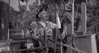 Movie still from “Creature from the Black Lagoon” (1954), directed by Jack Arnold – An older man sitting in a chair on a boat; Medium shot, Low angle