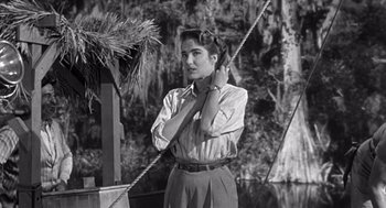 Movie still from “Creature from the Black Lagoon” (1954), directed by Jack Arnold – A woman standing in front of a tree holding a rope; Medium shot, Low angle