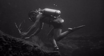 Movie still from “Creature from the Black Lagoon” (1954), directed by Jack Arnold – A man diving in the water with a scuba tank; Wide shot, High angle