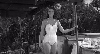 Movie still from “Creature from the Black Lagoon” (1954), directed by Jack Arnold – A woman in a white bathing suit standing under an umbrella; Medium shot, Low angle
