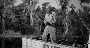 Movie still from “Creature from the Black Lagoon” (1954), directed by Jack Arnold – An older man standing on the side of a boat in the water; Medium shot, Low angle