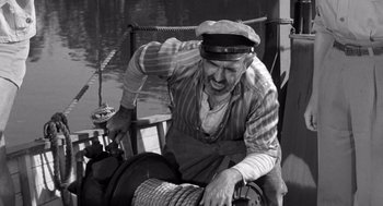 Movie still from “Creature from the Black Lagoon” (1954), directed by Jack Arnold – An old man wearing a hat and holding on to a rope; Medium shot, High angle