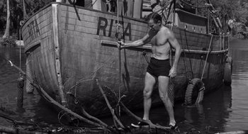 Movie still from “Creature from the Black Lagoon” (1954), directed by Jack Arnold – A man in shorts is pulling a rope on a boat; Wide shot, Low angle