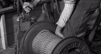 Movie still from “Creature from the Black Lagoon” (1954), directed by Jack Arnold – A person is pulling a rope on a spool; Extreme Close Up shot, Low angle