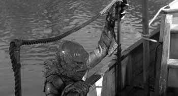 Movie still from “Creature from the Black Lagoon” (1954), directed by Jack Arnold – A creature from the black and white photo is hanging on a rope; Medium shot, High angle