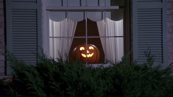 Movie still from “Creepshow” (1982), directed by George A. Romero – A pumpkin is lit up in the window of a house; Wide shot, Low angle