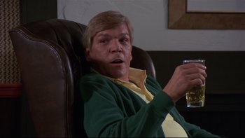 Movie still from “Creepshow” (1982), directed by George A. Romero – A man sitting in a leather chair holding a glass of beer; Medium shot, Low angle
